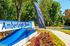 Welcoming entrance to Amberleigh Shores with vibrant landscaping, now leasing banner, and serene wooded backdrop.