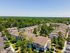 Aerial view of a serene apartment complex surrounded by lush greenery, showcasing rows of modern buildings and extensive parking space.