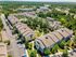 Bird's-eye view of a vibrant apartment complex surrounded by lush greenery, featuring multiple spacious buildings, a central sparkling pool, and ample parking.