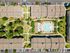 Aerial view of a modern apartment complex featuring a central resort-style swimming pool, surrounded by lush greenery and neatly arranged pathways.