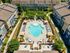 Chic apartment complex aerial view featuring a luxurious central swimming pool, surrounded by beautifully landscaped paths and colorful modern buildings.