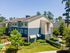 Charming apartment complex exterior with blue siding, lush landscaping, and a sunny pathway.