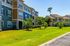 Charming apartment complex with colorful exteriors, lush green lawns, and inviting balconies under a clear blue sky.