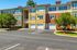 Charming three-story apartment building with colorful exterior, lush trees, and ample parking in a serene neighborhood.
