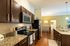 Modern kitchen with sleek granite countertops, stainless steel appliances, and pendant lighting opening to a cozy dining area with elegant decor.