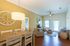 Bright and inviting living space with chic decor, featuring a cozy seating area, wooden dining table, and stylish wall clock.