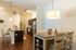 Inviting kitchen and dining area with modern lighting, hardwood floors, and sleek stainless steel appliances.