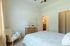 Bright and cozy bedroom with stylish decor, featuring a comfortable bed, plush armchair, and modern dresser.