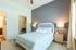 Bright and inviting bedroom with elegant gray accent wall, modern bedside lamps, and cozy bedding in a serene apartment setting.
