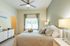 Bright and inviting bedroom with a cozy bed, modern decor, and natural light from a large window.