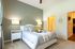 Bright and welcoming bedroom with tasteful decor featuring a cozy bed, elegant nightstands, and soft lighting, leading to a modern bathroom.