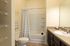 Elegant bathroom with modern fixtures, featuring a bright vanity, expansive mirror, and a cozy bathtub with chic chevron shower curtain.