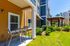 Charming apartment exterior with a cozy patio, modern seating, and vibrant landscaping under a clear blue sky.