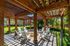 Inviting outdoor pergola with comfortable seating around a central fire pit, surrounded by lush greenery.