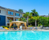 Inviting apartment complex with a sun-drenched pool and stylish poolside cabana, surrounded by lush greenery.