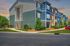 Charming modern apartment building with colorful siding, lush landscaping, and inviting walkways under a vibrant sunset sky.
