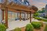Inviting outdoor patio with elegant wooden pergola, cozy seating area, and lush green surroundings at sunset.