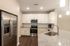 Modern kitchen with sleek stainless steel appliances, elegant granite countertops, and ample white cabinetry, illuminated by stylish pendant lighting.