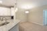 Modern apartment interior showcasing a sleek granite countertop, bright pendant lighting, and spacious carpeted living area.