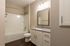 Modern bathroom with elegant granite countertop, sleek white cabinetry, and contemporary lighting above a spacious bathtub.