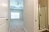 Inviting apartment view showcasing a bright bedroom with plush carpet, modern ceiling fan, and adjoining glass door shower.