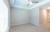 Bright and airy interior with plush carpet, modern ceiling fan, and abundant natural light from large window.
