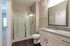 Elegant bathroom with modern glass shower, sleek granite countertop, and large mirror reflecting abundant natural light.