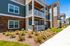 Modern apartment exterior featuring charming balconies, elegant stone accents, and vibrant landscaped gardens.