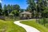Charming outdoor area featuring a fenced pet park with a cozy pavilion set amidst lush greenery and a clear blue sky.