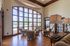 Elegant living area with large arched windows, cozy armchairs, and a view of the outdoor pool, creating a bright and inviting ambiance.