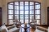 Elegant sitting area featuring plush armchairs and a wooden coffee table, with a breathtaking view of a luxurious pool through expansive windows.