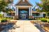 Inviting apartment complex entrance with elegant stone and wood design, lush landscaping, and welcoming seating area.