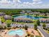 Stunning aerial view of a vibrant apartment community featuring a sparkling pool, lush greenery, and a tranquil pond, perfect for peaceful living.