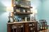 Charming coffee nook with wooden shelves, elegant lamps, and classic seating in a cozy, warmly-lit space.