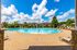 Inviting circular swimming pool surrounded by sun loungers and lush greenery under a bright blue sky.