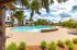 Inviting community pool surrounded by lush landscaping and elegant lounge chairs, perfect for relaxation and enjoyment under a bright blue sky.