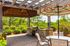 Charming outdoor patio with stone barbecue, vibrant umbrella, and lush greenery, perfect for entertaining.