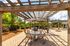 Charming outdoor patio with wooden pergola, stylish seating, and vibrant umbrellas, perfect for relaxing in a serene garden setting.