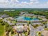 Stunning aerial view of a vibrant apartment complex with beautiful landscaping, a sparkling lake, and a refreshing pool, nestled in lush greenery.