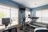 Modern fitness room with natural light featuring state-of-the-art treadmills and exercise bike positioned near large windows.