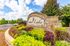 Picturesque entrance to Summer Lake Luxury Apartment Homes with vibrant landscaping and clear blue skies.