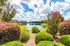 Serene lakeside view surrounded by lush greenery and vibrant flowers in a peaceful residential community.