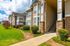 Charming apartment complex with elegant stone facades, lush green landscaping, and bright morning light.