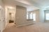 Bright and spacious open-concept living area with elegant chandelier lighting, plush carpet, and modern kitchen island.