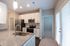 Modern kitchen featuring sleek grey countertops, stainless steel appliances, and elegant white cabinetry with ample natural light.