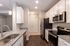 Modern kitchen featuring sleek white cabinets, granite countertops, and stainless steel appliances with stylish lighting.