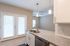 Modern kitchen with sleek granite countertops, stainless steel appliances, and bright natural light from French doors in a contemporary apartment.