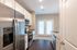 Modern kitchen with sleek stainless steel appliances, white cabinetry, and elegant hardwood floors leading to bright double patio doors.