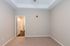 Bright bedroom with plush carpet and elegant tray ceiling, leading to a sleek hallway and modern bathroom.