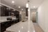 Modern kitchen with elegant dark wooden cabinets, sleek stainless steel appliances, and a spacious granite countertop island, offering a stylish and functional cooking space.